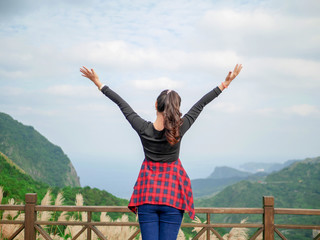 Fototapeta na wymiar Women wear black shirts Red scotch pattern and jeans.Standing relaxed, spread arms in the midst of nature on the mountain.