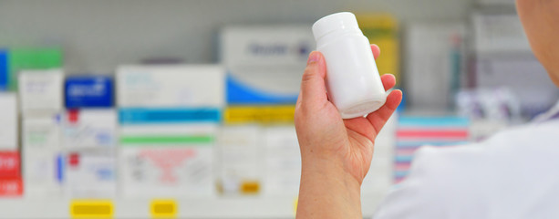 Pharmacist holding medicine bottle at the pharmacy drugstore 