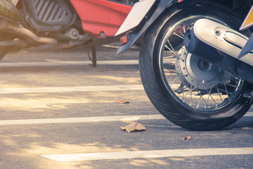 Close up wheel of motorcycle parked on parking lot.