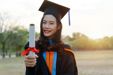 Female university graduate celebrates graduation ceremony receiving degree certificate happily with...