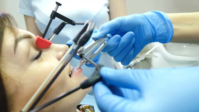Medicine, dentistry and health care concept. Part of dental technological process. Equipment for TMJ examining in modern dentist office. Close up shot of doctor and assistant setting transducer for