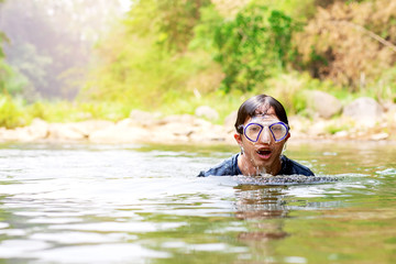 Asian man wearing diving goggles swimming in the river