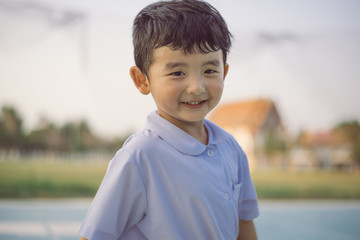 Outdoor portrait of a happy Asian student kid in school uniform smiling.