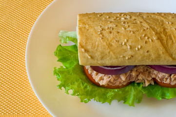 Tuna sandwich on white plate. Golden background.