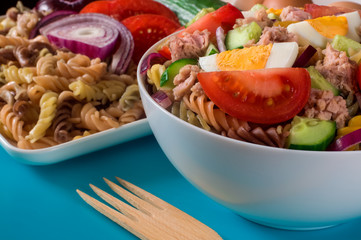 Traditional tuna salad on blue background. Wooden fork. Selective focus.