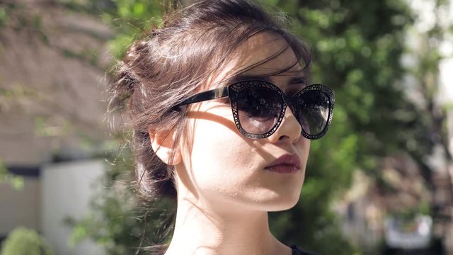 macro beautiful woman face with nude brown lipstick in big dark figured sunglasses under bright sunlight
