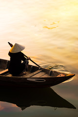 Vietnamese woman in traditional bamboo hat rowing