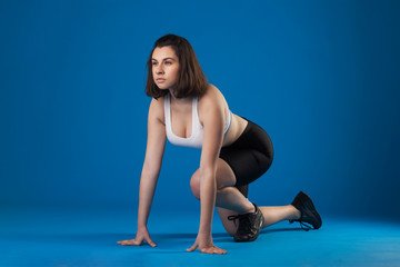 Brunette athlete girl on a blue background. studio photography