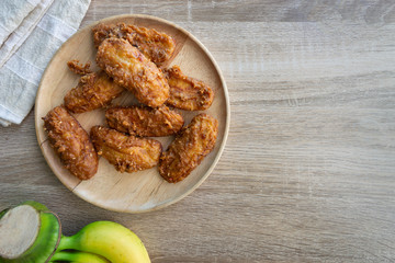 Deep fried banana in wooden dish with banana on table.