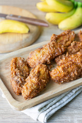 Deep fried banana in wooden dish with banana on table.