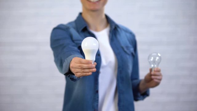 Girl chooses energy saving led bulb instead incandescent lamp, efficiency
