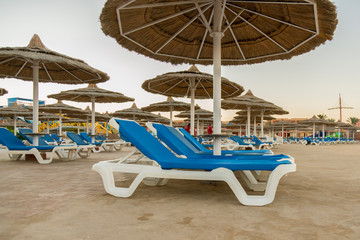 Umbrellas and chaise lounges on the beach. Scenic view of private sandy beach with sun beds from the sea