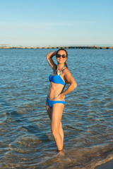 Fashion model in bikini posing at tropical beach. vertical photo. Beautiful sexy woman in bikini posing on beach