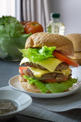 Hamburger with beef,cheese,lettuce,onion and tomato in white dish on concrete table.