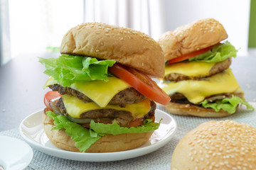 Hamburger with beef,cheese,lettuce,onion and tomato in white dish on concrete table.