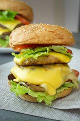 Hamburger with chicken,cheese,lettuce,onion and tomato on napery on the concrete table.