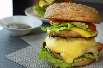 Hamburger with chicken,cheese,lettuce,onion and tomato on napery on the concrete table.