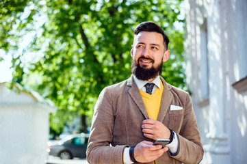 A successful bearded man holds a mobile phone