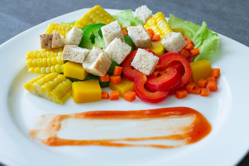 Healthy vegan,Salad with corn,pumpkin,carrot,bell pepper,lettuce and wheat bread in white dish on concrete table.