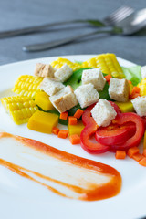 Healthy vegan,Salad with corn,pumpkin,carrot,bell pepper,lettuce and wheat bread in white dish on concrete table.