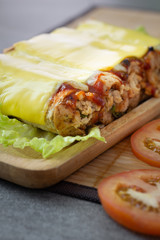 sandwich roll made with wheat bread stuffed chicken and tomato sauce topped up cheese in wooden dish on the concrete table.