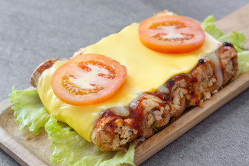 sandwich roll made with wheat bread stuffed chicken and tomato sauce topped up cheese in wooden dish on the concrete table.