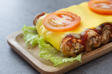 sandwich roll made with wheat bread stuffed chicken and tomato sauce topped up cheese in wooden dish on the concrete table.