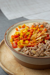 Beaten steamed egg with sweet pepper,carrot and chopped chicken in brown bowl on concrete table.