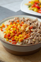 Beaten steamed egg with sweet pepper,carrot and chopped chicken in brown bowl on concrete table.