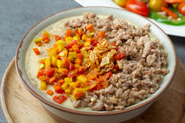 Beaten steamed egg with sweet pepper,carrot and chopped chicken in brown bowl on concrete table.