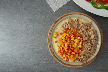 Beaten steamed egg with sweet pepper,carrot and chopped chicken in brown bowl on concrete table.