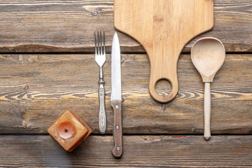 utensils with square candle and vintage cutlery on wooden background, top view 