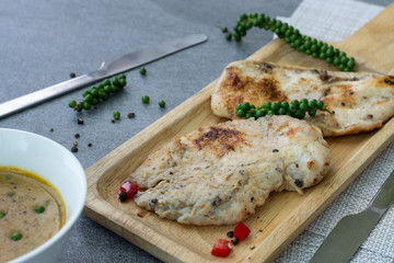 Fried chicken breast or chicken breast steak with black pepper in wooden dish on concrete table.