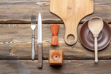 utensils with square candle and vintage cutlery on wooden background, top view 