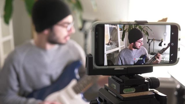 Musician vlogger recording a video of himself to post it on social media to be viewed by many viewers.