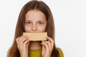 Portrait of a beautiful 8 year old girl in a sweater and with a wafer in her hands. White background