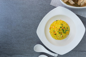 Fried rice with turmeric,carrot,egg and coriander or Yellow fried rice in white dish on concrete table.