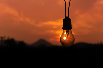 Light bulb with warm white on blur landscape background.