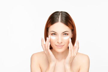 Naklejka premium Woman putting cream under eyes