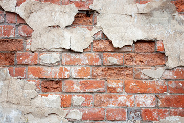Brick wall with fragments of plaster close-up. Fragment of the old brickwork. Potholes and red brick defects.