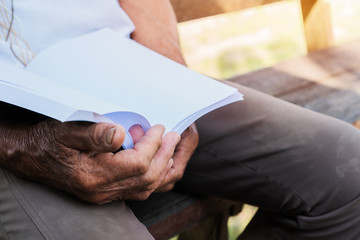 Obraz premium Adult education Learning Studying concept : Happy Asian Elderly retired man sitting reading book at garden home outdoor for learning or relax by self