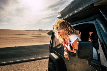Beautiful lady caucasian people female enjoy th ewind in the outdoor nature out of her black car - desert outdoor around and alternative vacation journey concept for cute young adult © simona