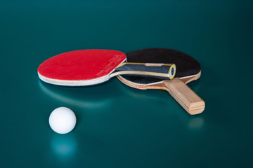 two ping-pong rackets and a ball on a green table.