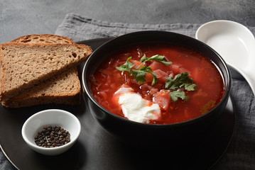 Traditional Ukrainian Russian borsch. Bowl of red beet root soup borsch with white cream on dark background. Beet Root delicious soup . Traditional Ukrainian food cuisine