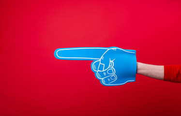 Handsome fan hand glove with foam finge, pointing away over red wall background