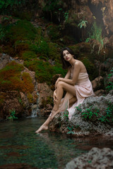 Beautiful girl posing in river. Fairytale story. Natural pool surrounded by green tree's leafs.