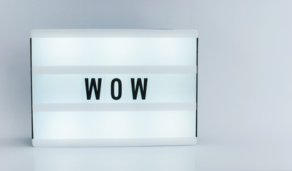 Photo of a light box with text, WOW, over isolated background wihte wall