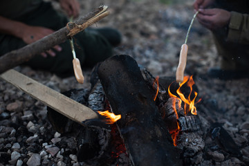 people fry sausages on an open fire