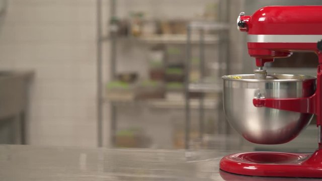 Left to right shot of the professional kneader spiral machine mixing dough for bread baking on blurred background.