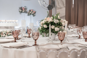 Flower arrangement in the center of the table. Interior of restaurant for wedding dinner, ready for...
